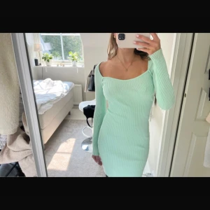 Mintgrön ribbad kortklänning - Superfin mintgrön ribbad klänning med lång ärm och figurnära passform. Klänningen har en snygg offshoulder-skärning och är perfekt för dig som gillar en stilren men trendig look. Materialet är stretchigt och bekvämt.