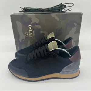 Valentino Rockrunner  - Snygga svarta Valentino Rockrunner sneakers med detaljer i vinrött och grått. Perfekta för dig som vill sticka ut med stil. Skorna är strl 40 men passar som 41. Nypris ca 7300kr. Rengjorda och är som nyskick. Pris kan diskuteras vid snabb affär:)
