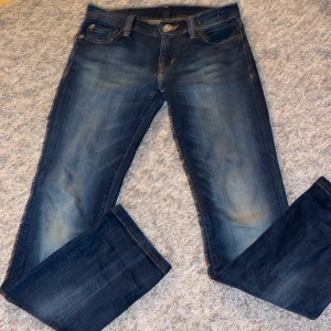 Mörkblå jeans från Ralph Lauren/Denim - Säljer ett par snygga mörkblå jeans från Denim & Supply Ralph Lauren. Jeansen har klassisk femficksdesign, raka ben och coola slitningar framtill. De är tillverkade i mjukt jeanstyg och har en snygg tvättad look med kontrastsömmar.