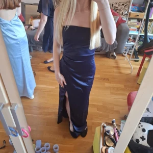 Marinblå klänning - Säljer en marinblå axelbandslös långklänning i glansigt satin material. Klänningen har en snygg slits framtill. Perfekt för bal eller festliga tillfällen. Endast använd en gång och säljer då den inte kommer komma till användning.💓