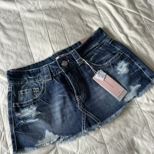 Lågmidjad Blå jeanskjol från Gina Tricot Young - Snygg blå jeanskjol från Gina Young 14+ med slitna detaljer och fransig nederkant. Kjolen har klassiska fickor fram och bak, bälteshällor och markerade sömmar. Perfekt för dig som gillar en cool och avslappnad stil. Helt ny med lappar kvar men tyvärr för stor för mig! Helt slutsåld i strl M!