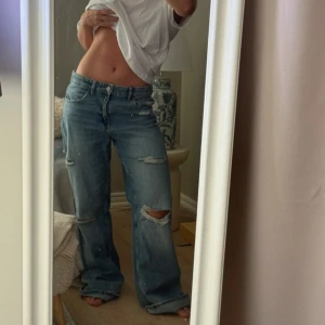 Blå baggy jeans med slitningar - Säljer ett par ljusblå baggy jeans med slitna detaljer och hål på knäna. Jeansen har normal midja, raka ben och klassisk femficksdesign. Perfekta för en avslappnad och trendig look. Inte mina egna bilder! Helt nya med prislapp kvar. Säljer pga. Att dom tyvärr var för stora på mig!❤️