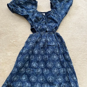 Blå kortklänning med puffärmar från Zara - Supersöt blå kortklänning från Zara med ljusblått mönster, puffiga kortärmar och elastisk midja. Klänningen har en luftig passform och är gjord i mjuk bomull, perfekt för varma dagar. Snygg volangkant nertill och cool cut-out vid midjan.