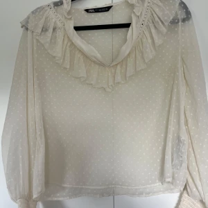 Somrig och tunn blus - En tunn och trevlig v-ringad blus från Zara med volang. Den har en avslappnad passform och passar storlekarna XS-M, blusen har tyvärr aldrig kommit till användning och är helt ny!