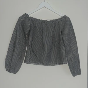 Randig offshoulder blus Brandy Melville - Säljer en svartvit randig offshoulder blus från Brandy Melville. Blusen har långa ärmar med resår vid ärmslut och en luftig passform. Perfekt för dig som gillar en chill och trendig stil.