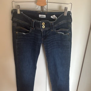 Mörkblå jeans Pepe Jeans Power Flex - Snygga mörkblå jeans från Pepe Jeans Power Flex med raka ben och dubbla guldknappar i midjan. Klassisk femficksmodell med kontrastsömmar och diskret broderad bakficka. Stretchigt jeanstyg för extra komfort. 🥰❤️ Midjemåttet är ca 36 cm, det är super låg missade på mig 💗