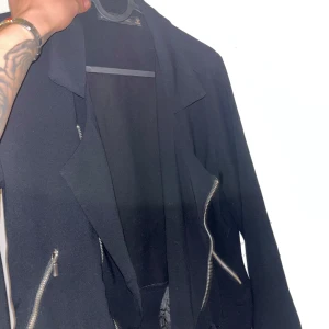 Svart bomberjacka från Zara Basic - Snygg svart bomberjacka från Zara Basic med coola silverfärgade dragkedjor och klassisk krage. Jackan har långa ärmar och två fickor framtill med dragkedja. Perfekt för dig som vill ha en stilren och enkel look.