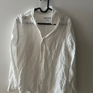Vit linneskjorta från Zara slim fit - Vit långärmad skjorta från Zara i slim fit-modell. Skjortan är tillverkad i svalt linne och har klassisk krage samt knäppning framtill. Perfekt för en clean och fräsch look under varmare dagar.