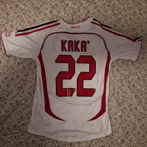 AC Milan Kaka' 22 Champions League tröja - AC Milan bortatröja från Champions League-finalen 2007 med Kaka' och nummer 22 på ryggen. Adidas, vit med röda och svarta detaljer, kortärmad och tillverkad i 100% polyester. Klassisk Bwin-sponsor och klubbmärke på bröstet.