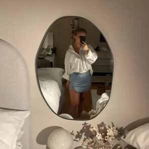 Ljusblå jeanskjol med slits - Säljer en ljusblå jeanskjol i klassisk modell med liten slits framtill. Kjolen har en tight passform och är i kort längd, perfekt till sneakers eller boots. Enkel och stilren design utan mönster, passar till många olika looks. 