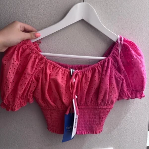 Rosa croppad blus med puffärm - Superfin rosa croppad blus med broderade hål och puffiga korta ärmar. Köpt på sellpy’ 