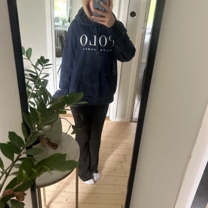 Mörkblå hoodie från Polo Ralph Lauren - Säljer en mörkblå hoodie från Polo Ralph Lauren med stor vit logga framtill. Tröjan har huva med snörning. Perfekt för dig som gillar stilrena och bekväma plagg. Storlek M. Säljer pga köpte fel storlek.