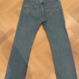 Blå jeansbyxor från Crocker Basic - Klassiska blå jeansbyxor från Crocker Basic med raka ben och normal passform. Jeansen har fem fickor, gylf med dragkedja och är tillverkade i 100% bomull. Perfekta för en avslappnad stil.