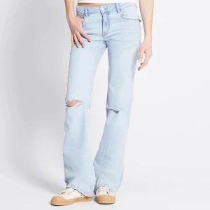 Ljusblå bootcut jeans med hål på knät      Xs full length  - Säljer ett par ljusblå jeans med bootcut passform och ett snyggt hål på ena knät. Jeansen har klassisk femficksdesign . Perfekta för en avslappnad och trendig look.