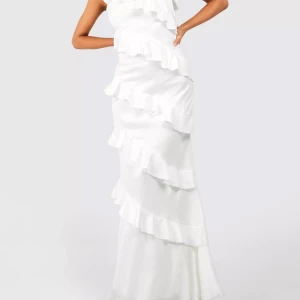 Vit långklänning med volanger - Säljer en elegant vit långklänning med smala axelband och flera volangdetaljer längs hela klänningen. Perfekt för speciella tillfällen när du vill sticka ut med en stilren och romantisk look.