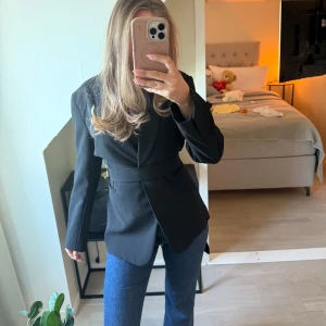 Svart kavaj med bälte - Super snygg svart kavaj med snöre som man kan knyta i midjan om man vill. Man kan knyta både fram och bak precis som jag visat på bilderna. Men även super snygg att ha som den är utan bandet! ❤️ Storlek 42 men passar absolut även mindre. Jag själv brukar ha 38 i kavaj men gillar den mer oversized looken.