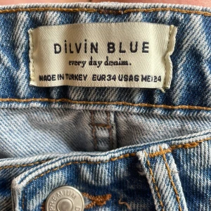 Blå jeans från Dilvin Blue - Säljer ett par klassiska blå jeans från Dilvin Blue. Jeansen har normal passform, hög midja och raka ben. Tillverkade i denim med snygga detaljer och knappstängning framtill. Perfekta för en avslappnad stil.