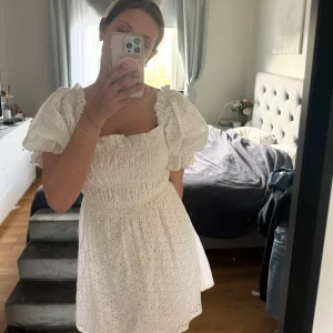 Vit somrig klänning  - Superfin vit kortklänning med puffiga kortärmar och broderade hålbroderier. Perfekt för studenten och sommarens alla tillfällen!  Oanvänd och har prislappen kvar. Skriv för fler bilder 