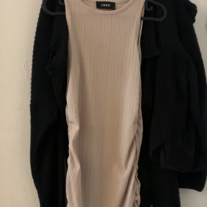 Beige ribbad ärmlös klänning från Cider - Säljer en beige ribbad klänning från Cider. Klänningen är ärmlös med rund halsringning och har en tight passform. Detaljer på sidorna 