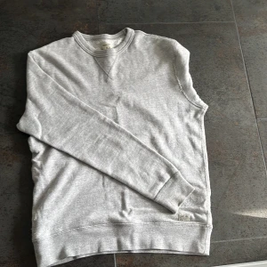 Grå sweatshirt från Denim & Supply Ralph Lauren - Säljer en klassisk grå sweatshirt från Denim & Supply Ralph Lauren. Tröjan är i mjuk bomull med rund halsringning och ribbade muddar vid ärmslut och nederkant. Perfekt för en avslappnad stil.