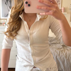 Vit kofta med knappar - Säljer en klassisk vit kofta med trekvarts ärmar och knappar framtill. Kofta  har en enkel och stilren design som passar till många olika outfits. Perfekt för dig som gillar en clean och fräsch look.