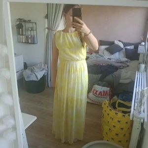 Gul långklänning med öppen rygg / balklänning / sommar klänning  - Säljer en somrig gul långklänning med vitt mönster. Klänningen har ärmlös design, markerad midja och en snygg öppen rygg. Tyget är lätt och luftigt, perfekt för varma dagar. Har en slits som går upp till knäna ungefär. Även ett undertyg som gör att man inte ser igenom klänningen som går ner till slitsens början. Från Bikbok, strl S 