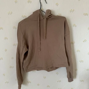  hoodie  - Säljer en beige croppad hoodie från Vero Moda Aware. Tröjan har långa ärmar, huva med dragsko och är tillverkad i mjukt material. Perfekt för en avslappnad stil.