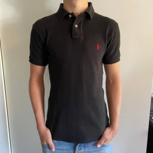 Svart pikétröja från Polo Ralph Lauren - Säljer en Svart Pike från Polo Ralph Lauren i storlek S Slim Fit. Tröjan har inga defekter och är perfekt nu till sommaren! 🏖️Modellen är 177cm. Tveka inte på att skriva om du har frågor eller funderingar!  Priset är såklart inte hugget i sten 🪨 