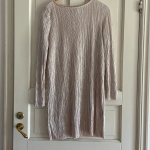 Ljusbeige plisserad klänning från Gina Tricot - Säljer en ljusbeige plisserad klänning från Gina Tricot. Klänningen har lång ärm, rund halsringning och är tillverkad i ett glansigt, syntetmaterial med diskret struktur. Perfekt för dig som gillar stilrena och enkla plagg.