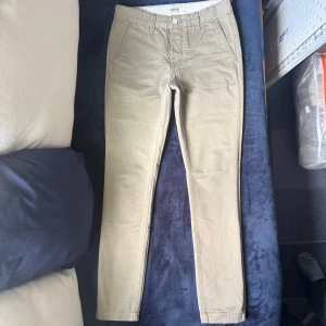 Beiga chinos från Dobber - Snygga beiga chinos från Dobber med slimmad passform och raka ben. Klassisk design med fickor fram och bak, samt knappdetaljer bak. Perfekta till både skjorta och t-shirt.