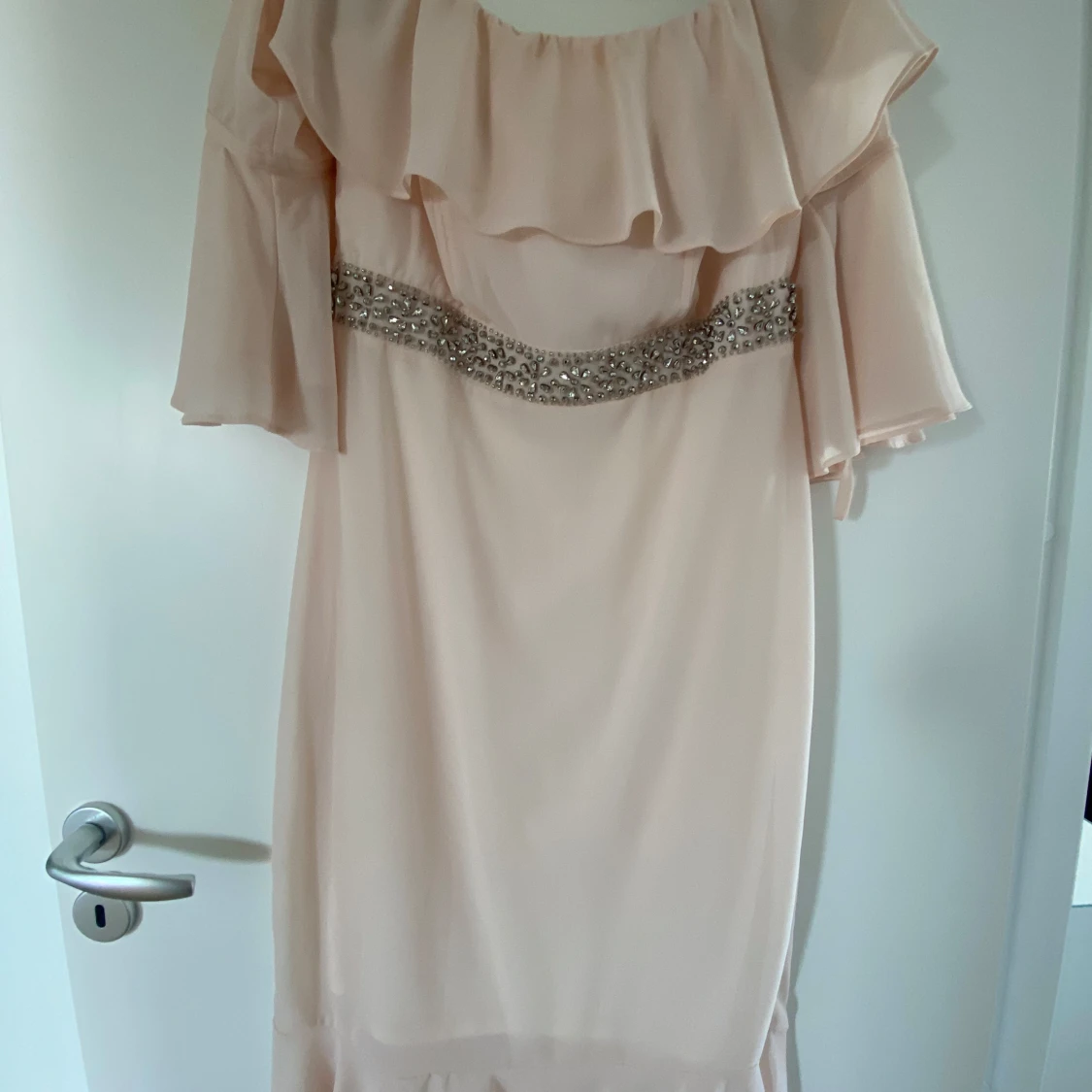 Ljusbeige offshoulder klänning med volang och pärldetaljer från Sisters Point