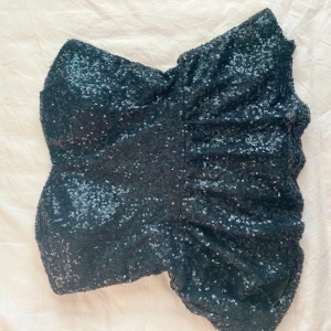 Svart glittrig festtopp - Svart glittrig tubtopp som aldrig är använd. Den har inlägg i sig så att man inte behöver ha bh, men funkar att ha det ändå om man vill. Den är M men den sitter bra på mig och skulle säga att den sitter mer som en S. Det är en dragkedja på sidan oxh den kan vara lite seg men funkar🩷