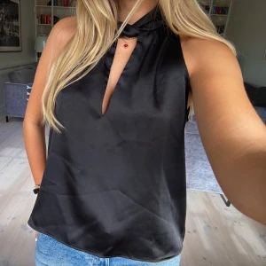 Svart  topp med krage - Svart ärmlös blus i satinliknande material med hög krage och v-ringad öppning framtill. Superbra skick 💘