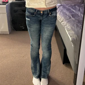 Blå bootcut jeans - Midjemått rakt över 33cm inerbenslengden 73 cm. Säljer ett par klassiska blå bootcut jeans med lätt slitning och normal passform. Jeansen har fem fickor, knapp och dragkedja framtill samt en snygg tvättad look. Perfekta till vardags för en avslappnad stil.