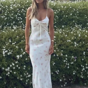 Vit blommig långklänning - Säljer den populära Zara klänningen! Super fin! Obs: klänningens band är klippta så istället för att knyta runt ryggen så knyter man runt halsen! Inget som påverkar passformen enligt mig (kom privat för bild). Dragkedjan är lite seg men annars är den i ett bra skick. 