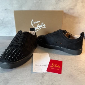 “Christian Louboutin Louis Spikes Veau Velours – Svart Sammet med Röd Revolt” - Den svarta sammeten ger skon en lyxig och sofistikerad känsla, medan de ton-i-ton glänsande nitarna framtill tillför precis rätt mängd attityd. Detaljerna är genomtänkta, designen är tidlös – och den ikoniska röda sulan påminner om att stil alltid börjar underifrån. Perfekta för dig som uppskattar subtil extravagans och kompromisslös kvalitet. 