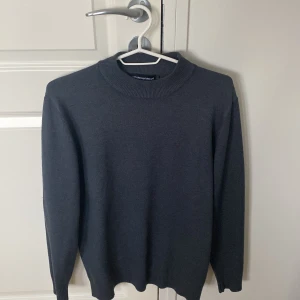 Mörkgrå stickad tröja från Emporio Armani - Säljer en stilren mörkgrå stickad tröja från Emporio Armani. Tröjan har rund halsringning, diskret broderad logga på bröstet och långa ärmar. Storlek men passar bra på mig som har storlek S tight fit