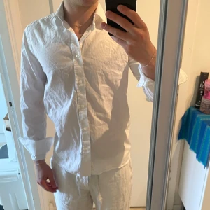 Vit skjorta från Bläck - Klassisk vit skjorta från Bläck i modellen Tailored Fit. Skjortan har lång ärm, knappar framtill och en stilren krage. Perfekt för dig som gillar en clean och enkel look. Tillverkad i bomull för en skön känsla. Bra skick, storlek XS men passar även S