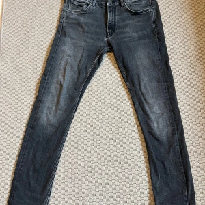 Svarta jeans från GANT - Säljer ett par svarta jeans från GANT med klassisk femficksdesign och raka ben. Jeansen har knapp och dragkedja i gylfen samt diskreta slitningar för en snygg look. Perfekta för dig som gillar stilrena och bekväma jeans.