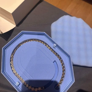 Guldplaterat halsband med gnistrande kristaller från Swarovski - Elegant halsband guldplaterat från Swarovski, dekorerat med runda, gnistrande kristaller längs hela bandet. Kommer i en lyxig blå ask med svanlogga. Perfekt för att ge en extra touch