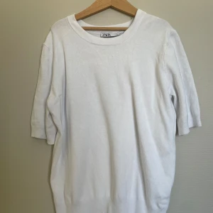 Vit kortärmad tröja från Zara - Säljer en enkel och stilren vit tröja från Zara. Tröjan har korta ärmar och rund halsringning. Materialet känns mjukt och passar perfekt till många olika outfits.