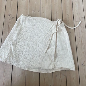 Somrig omlott kjol - Säljer en  omlottkjol. Kjolen har knytband vid sidan av midjan:) säljer då den tyvärr inte passar mig längre 