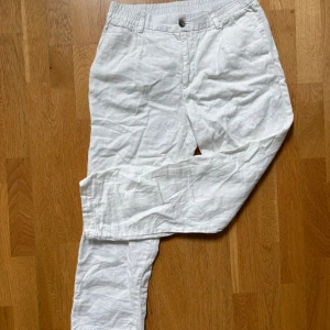Vita linnebyxor från H&M, regular fit - Snygga vita linnebyxor från H&M i regular fit. Byxorna har klassisk design med knapp och dragkedja, samt fickor fram. Perfekta för varma dagar och ger en fräsch och avslappnad look.