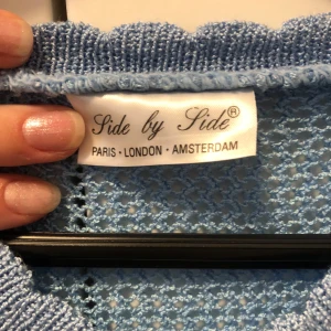 Ljusblå stickad tröja Side by Side - Supersöt ljusblå stickad tröja från Side by Side med v-ringning och lång ärm. Tröjan har ett genombrutet mönster och meshstickade partier upptill och på ärmarna. Perfekt för lager-på-lager och ger en chill men ändå snygg vibe.