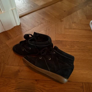  Isabel Marant skor  - Säljer ett par svarta sneakers från Isabel Marant i mocka med snörning och gummisula. Skorna har rund tå och diskreta sömdetaljer längs sidorna. Perfekta för dig som gillar stilrena och bekväma skor.