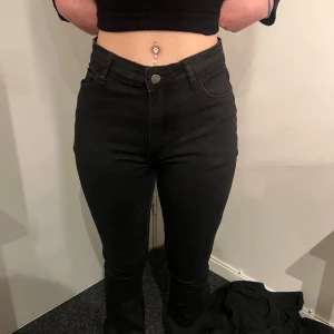 Svarta högmidjade skinny jeans - Säljer ett par svarta högmidjade skinny jeans med klassisk femficksdesign och knappgylf. Jeansen har en tight passform och är perfekta till vardags. Snygga att matcha med crop top eller stickad tröja.
