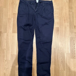 Boomerang chinos mörkblå - Snygga mörkblå chinos med normal passform och klassisk design. Byxorna har knäppning fram och sidofickor, perfekta för en stilren look. Tillverkade i mjukt bomullsmaterial som känns bekvämt hela dagen.