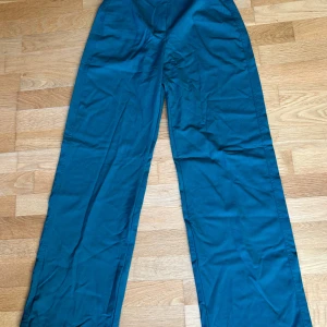 Gröna kostymbyxor från Bershka - Säljer ett par gröna kostymbyxor från Bershka med normal passform och vida ben. Byxorna har hög midja, knapp och dragkedja framtill. Perfekta för en stilren look och passar till många olika outfits. Finns inte kvar på Bershkas hemsida derför beiga byxor på sista bilden. Aldrig använda