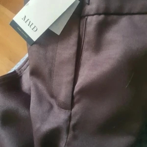 Bruna kostymbyxor från Ahlvar Gallery - Snygga bruna kostymbyxor från Ahlvar Gallery med klassisk passform och diskret dragkedja. Byxorna har en elegant look och är perfekta för en stilren outfit. Materialet känns mjukt och har en lätt glans. Ej använda Nypris 1799 kr 