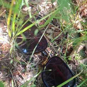 Svarta solglasögon från Prada med gulddetaljer - Snygga solglasögon från Prada med svart båge, gulddetaljer och röda skalmar. Rektangulär form och mörka glas. Märkeslogga synlig på sidan. Perfekt accessoar för att lyfta din stil. Priset kan diskuteras